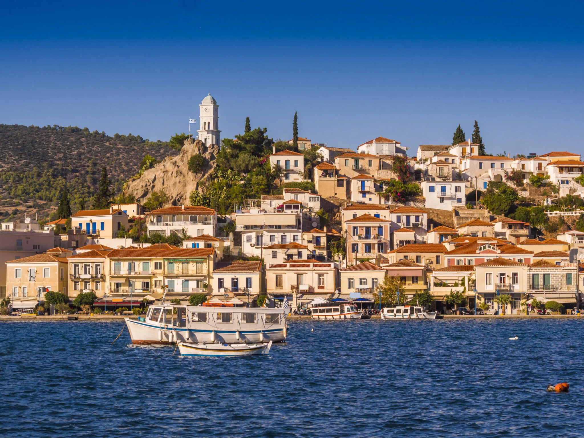 Poros-Uferpromenade mit bunten Gebäuden und Uhrturm, Saronischer Golf Griechenland